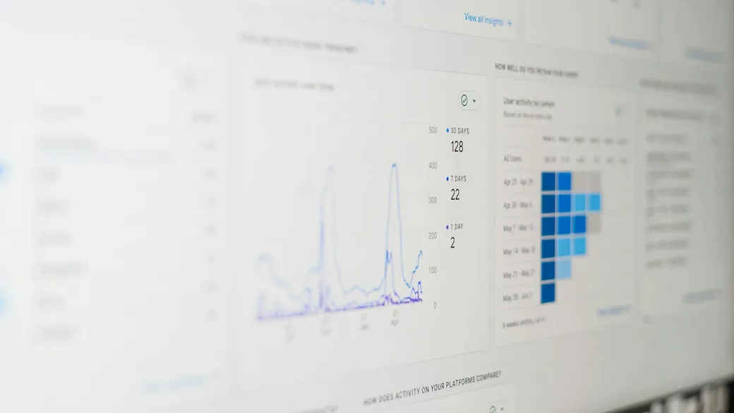 An analytics dashboard on a monitor showing a traffic line chart beside a weekly user retention grid